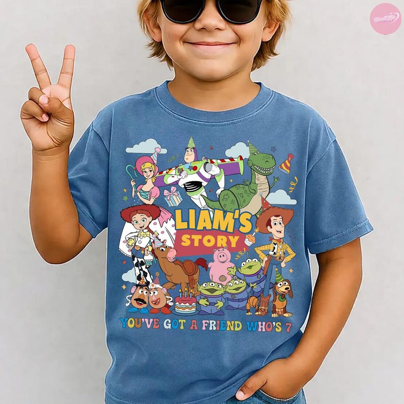 May include: Blue t-shirt featuring a colorful graphic of characters from the animated film Toy Story. The shirt includes the text "Liam's Story" and "You've Got a Friend Who's 7". The design includes Woody, Buzz Lightyear, and other characters.