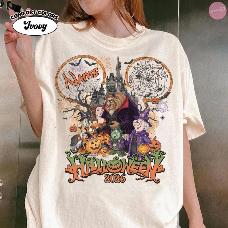 May include: An ivory t-shirt featuring a graphic print of characters from Beauty and the Beast in a Halloween setting. The design includes a castle, spiderwebs, pumpkins, and the text "Name" and "Halloween 2026" in orange and black lettering.