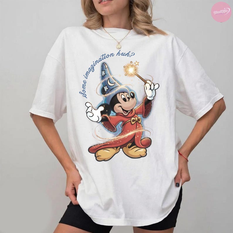 K&ouml;nnte beinhalten: Wei&szlig;es T-Shirt mit einem Cartoon-Mickey-Mouse-Zauberer-Design, der einen Zauberstab mit einem Funkel-Effekt h&auml;lt. Der Text "Some imagination huh?" ist in einer Schreibschrift geschrieben. Das Design verwendet Rot-, Blau- und Gelbt&ouml;ne.