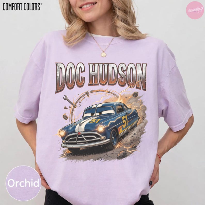 May include: Orchid Comfort Colors t-shirt featuring a graphic of Doc Hudson's car from the movie Cars. The design includes the text "DOC HUDSON" above the car, with a racing number "51" on the car's side.