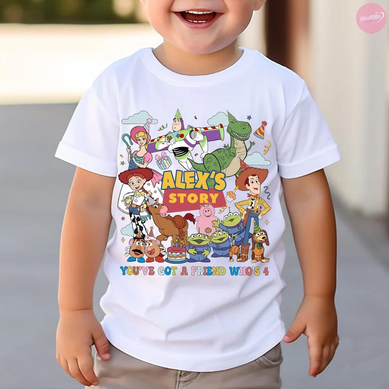 May include: White t-shirt featuring a colorful graphic of characters from the animated film "Toy Story." The design includes the text "ALEX'S STORY" and "YOU'VE GOT A FRIEND WHO'S 4."