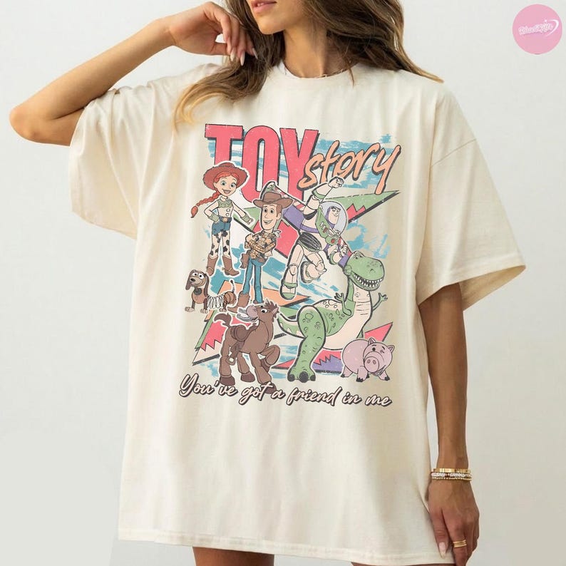 Puede incluir: Camiseta color crema con un gr&aacute;fico colorido de los personajes de Toy Story, incluyendo a Woody, Buzz Lightyear y Rex. El texto "TOY STORY" se muestra encima de los personajes, con la frase "You've got a friend in me" debajo.