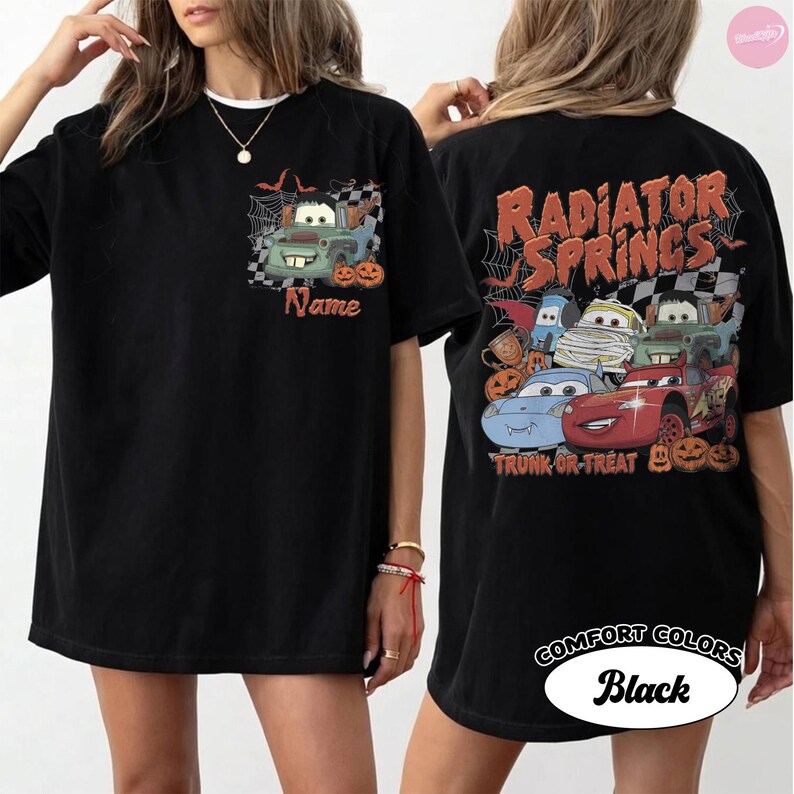May include: A black t-shirt featuring a front pocket graphic of a green truck character with spiderwebs and pumpkins, and a large back graphic with the text Radiator Springs and Trunk or Treat, depicting multiple car characters in Halloween costumes.