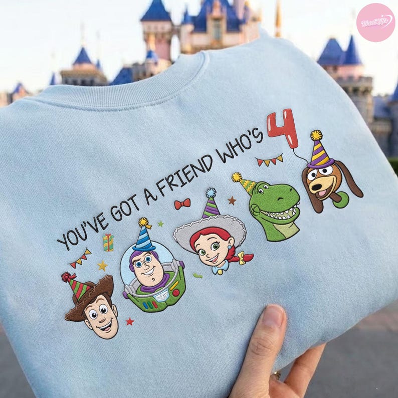 K&ouml;nnte beinhalten: Hellblaues Sweatshirt mit dem Text "YOU'VE GOT A FRIEND WHO'S 4" und Cartoonfiguren. Mit Woody, Buzz Lightyear, Jessie, Rex und Slinky Dog mit Partyh&uuml;ten. Ein roter Ballon mit der Zahl 4 ist ebenfalls enthalten.