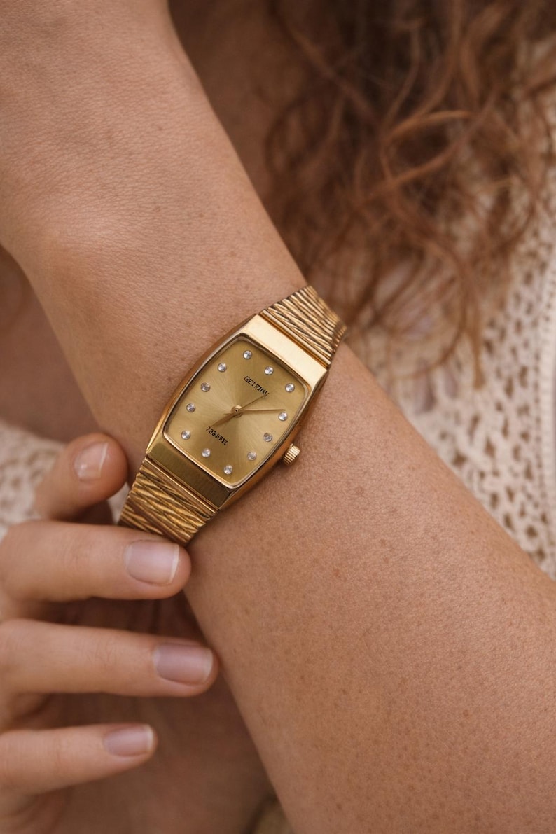 Vintage gold tone women’s watch from the 1980s worn on a female wrist, featuring a rectangular case and elegant gold bracelet