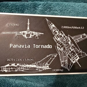 May include: A black and white line drawing of a Panavia Tornado fighter jet. The drawing includes the jet's dimensions, speed, and weight. The text reads: "1,390(km)" "Panavia Tornado" "2,400(km/h)Mach 2.2" "16.72 x 13.91 x 5.95(m)" "14,500(kg)"