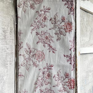 May include: A white fabric with vertical stripes and a burgundy floral pattern. The design features roses and other flowers with detailed leaves, creating a vintage aesthetic. The fabric is likely used for home decor.