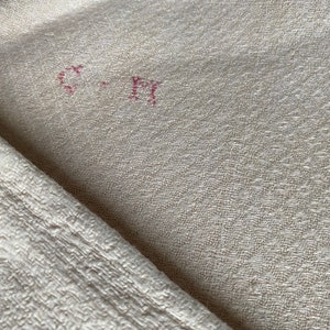 May include: Close-up of a white fabric with a textured surface. The fabric has a red stamp that says "C-F1" in the center.