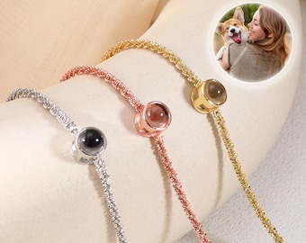 May include: Three delicate bracelets in silver, rose gold, and gold, each featuring a small, round charm. The charms appear to hold a miniature image. A circular inset shows a woman with a dog. The bracelets are displayed on a soft, neutral surface.