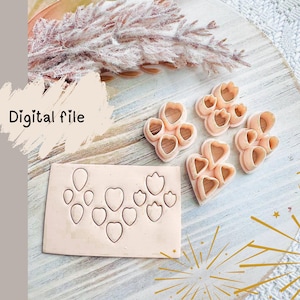 May include: A collection of pink polymer clay cutters in various heart and floral shapes. The cutters are arranged on a light-colored wooden surface, with a piece of clay showing the cut-out shapes. The words "Digital file" are written on the image.