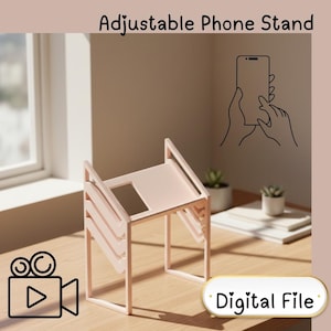 May include: A light pink adjustable phone stand on a wooden surface. The stand has a rectangular base and a slatted design. The text "Adjustable Phone Stand" is at the top, and "Digital File" is in a rounded rectangle.