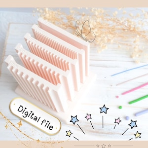 Può includere: Un portafoglio digitale rosa chiaro con fessure angolate contrassegnate 2 mm, 3 mm, 4 mm e 5 mm. Il supporto è su una superficie bianca con un'illustrazione di farfalla e le parole "Digital file". Sono visibili anche stelle decorative e forniture artigianali colorate.