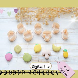May include: A collection of light pink bead cutters in various shapes, including a mushroom, lemon, and strawberry. The image also features several light pink cutters and fruit-shaped beads. A pink tag reads "Bead Cutters."