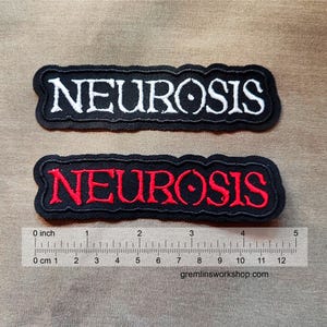 Op de afbeelding: Twee zwarte stoffen patches met het woord "NEUROSIS" geborduurd in witte en rode draad. De patches zijn ongeveer 10 cm lang en 2,5 cm breed.