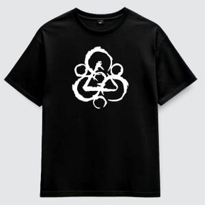 Può includere: T-shirt nero con un design astratto bianco. Il design include un triangolo, cerchi e altre forme geometriche. La maglietta ha maniche corte e girocollo.