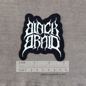 Puede incluir: Parche negro con la inscripción blanca "BLACK ARAID" en letras estilizadas. El parche mide aproximadamente 7.6 cm de ancho. El sitio web gremlinsworkshop.com está impreso en la parte inferior.