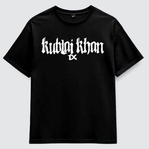 Może przedstawiać: Czarny t-shirt z krótkim rękawem z białym napisem Kublai Khan TX nadrukowanym na klatce piersiowej. Odzież posiada okrągły dekolt i standardowy krój, prezentując wyrazisty wzór graficzny wykonany białą farbą na czarnym materiale tekstylnym.