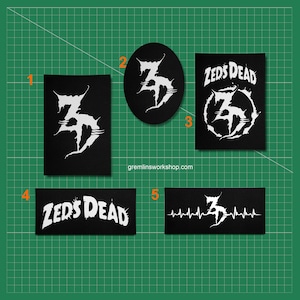 Op de afbeelding: Een verzameling zwart-witte patches met de tekst "Zeds Dead" en een gestileerd "Z"-logo. De patches hebben verschillende vormen, waaronder rechthoekige en ovale ontwerpen. De website gremlinsworkshop.com is zichtbaar.