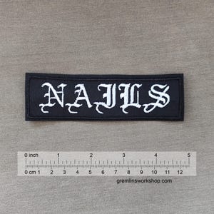 Puede incluir: Parche bordado negro con letras blancas que dicen "NAILS".