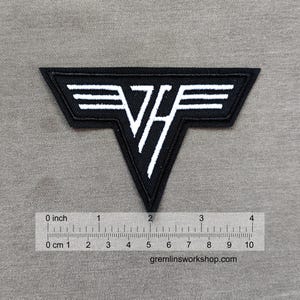 Könnte beinhalten: Schwarz-weißer, gestickter Aufnäher mit den Buchstaben "VH" in einem stilisierten Design. Der Aufnäher ist etwa 10 cm breit und hat einen schwarzen Rand und weiße Schrift. Die Website gremlinsworkshop.com ist unten sichtbar.