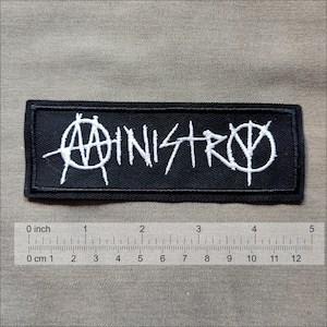 May include: Black and white embroidered patch with the word "Ministry" in a stylized font.