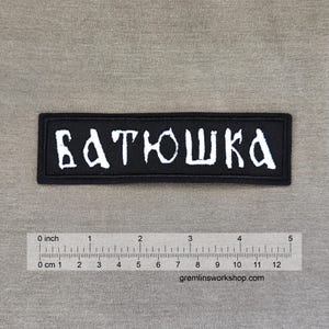 May include: Black embroidered patch with white lettering that reads "Батюшка".