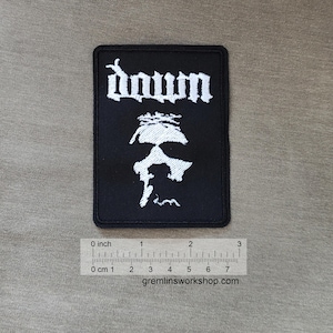 May include: Black embroidered patch with the word "Down" in white lettering and a white silhouette of a person's face.
