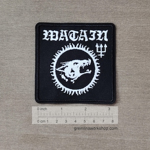 May include: Black square patch with the word "WATAIN" in white gothic lettering. A white circular design features a snarling wolf and a trident symbol. The patch measures approximately 3 inches wide.