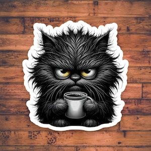 May include: A black cat with a grumpy expression holds a white coffee mug. The cat has a thick, shaggy coat and yellow eyes.