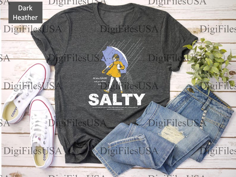 May include: Dark heather gray t-shirt with a graphic of a person under an umbrella in the rain, with the word "SALTY" in white. The shirt is paired with blue jeans and white sneakers.