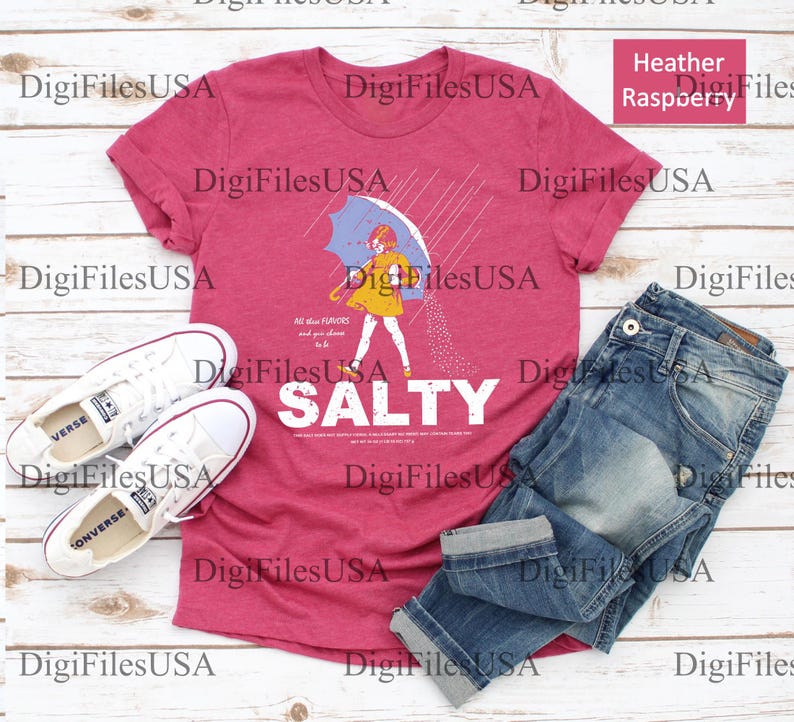 May include: Heather raspberry t-shirt with a graphic of a person under an umbrella, with the word "SALTY" in white. The shirt is paired with blue jeans and white sneakers.