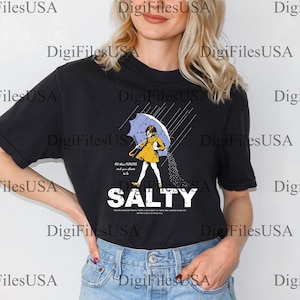 May include: Black t-shirt featuring a graphic of a person under an umbrella, with the word "SALTY" in bold white letters. The illustration includes the text "All the flavors and you choose to be".