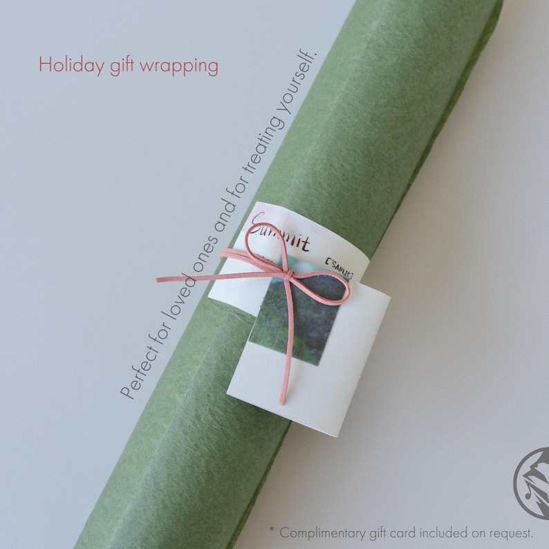 May include: A rolled-up green gift wrap with a pink ribbon and a small white tag. The tag has the word "Summit" and a small image. Text on the image reads "Holiday gift wrapping" and "Perfect for loved ones and for treating yourself."