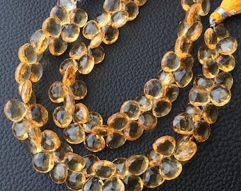 May include: Three strands of faceted, teardrop-shaped citrine beads. The beads are a warm, golden-yellow color and are strung together. The strands are arranged in a layered pattern. Tassels with orange and silver accents are visible at the top.