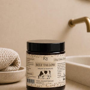 Könnte beinhalten: Ein dunkelbrauner Kunststofftiegel mit Rindertalg der Marke RY und schwarzem Schraubdeckel. Das Etikett zeigt eine Kuh-Illustration sowie den Text "BEEF TALLOW ORGANIC & GRASS FED", "Tallow, Ascorbyl Palmitate (Vitamine C)" und "100 G / 3.5 OZ" auf gesprenkeltem Grund.