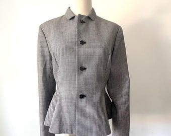 May include: A black and white houndstooth patterned blazer with a fitted bodice and a peplum hem. The blazer has a collar and five black buttons.