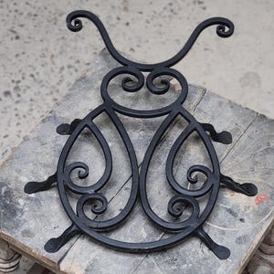 Puede incluir: Diseño de mariquita de metal negro con intrincados remolinos y curvas. El diseño está hecho de hierro forjado y tiene un aspecto rústico y hecho a mano.