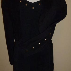 May include: A black dress with a matching jacket. The dress has a sweetheart neckline and a gold studded belt. The jacket has long sleeves and a V-neck.