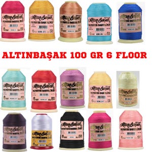 Könnte beinhalten: Eine Sammlung bunter Altinbasak Polyestergarnspulen. Die Spulen sind in verschiedenen Farbtönen erhältlich, darunter Rosa, Gelb, Blau und Lila. Der Text "ALTINBAŞAK 100 GR 6 FLOOR" ist rot dargestellt.