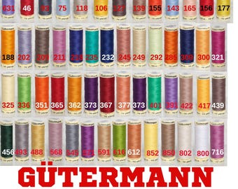 Op de afbeelding: Een verzameling Gütermann garenspoelen in verschillende kleuren, waaronder rood, blauw, groen en geel. Elke spoel is voorzien van een nummer en de merknaam Gütermann. De afbeelding is een close-up van de garenspoelen.