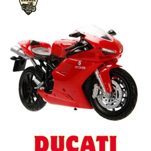 May include: A red Ducati 1198 motorcycle model featuring black wheels, a clear windscreen, and silver exhaust pipes. The text MOTO GARAGE 2024 appears in a shield logo at the top left, with the text DUCATI 1198 displayed in large red and grey font below.