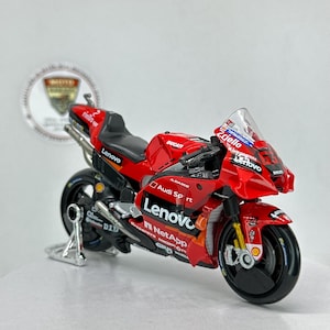 Peut inclure: Modèle réduit de moto Ducati rouge et noire avec les marques Lenovo et NetApp. Le modèle a un pare-brise transparent et une béquille argentée. La moto est une réplique détaillée d'une moto de course.