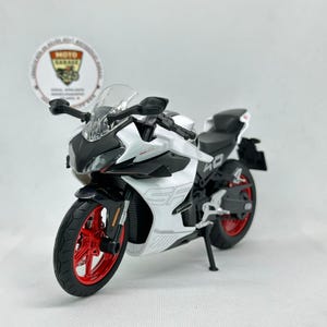 May include: A white and black toy motorcycle with red wheels. The motorcycle has the text "SF" on the side and the number "40" on the back. The motorcycle has a clear windscreen and black handlebars.