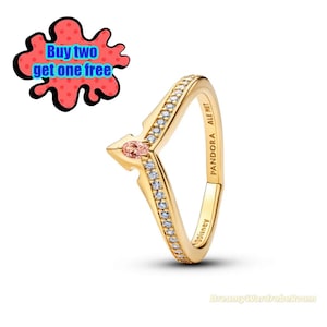 以下が含まれることがあります： 小さなピンク色の宝石とクリアストーンをあしらった、V字型のデザインのゴールドリング。「PANDORA ALE MET」と「©Disney」の刻印入り。赤と黒のグラフィックには「Buy two get one free」と書かれています。