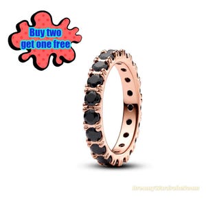 May include: Rose gold ring with a full band of black gemstones. The ring is set against a white background. A red and black graphic with the text "Buy two get one free" is in the upper left corner.