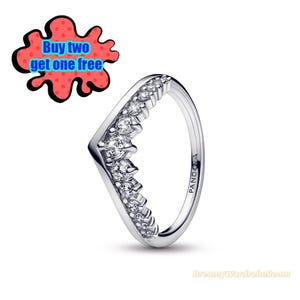 Puede incluir: Un anillo plateado con un diseño en forma de V, adornado con múltiples piedras preciosas transparentes. El anillo tiene la marca "PANDORA" grabada en el lateral. Un gráfico rojo y negro con el texto "Buy two get one free" está en la esquina superior izquierda.