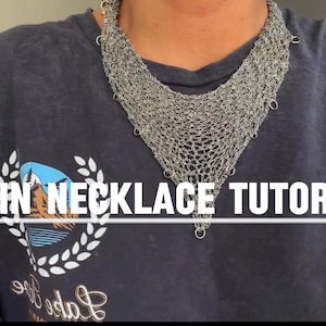 Op de afbeelding: Een zilverkleurige maliënkolder ketting met een V-vormige drapering, voorzien van een complex patroon van in elkaar grijpende metalen ringen. De tekst "CHAIN NECKLACE TUTORIAL" staat in witte hoofdletters over het midden van de afbeelding.