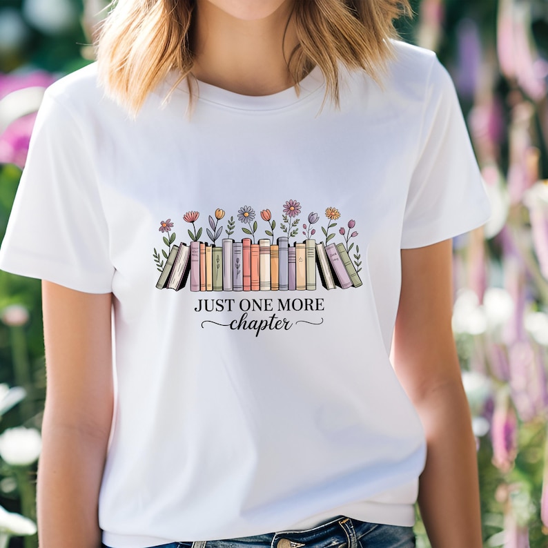 May include: White t-shirt with a graphic of books and flowers, and the text "JUST ONE MORE chapter". The design features a row of books with colorful spines, and various flowers. The text is in a decorative font.