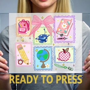 May include: A clear sheet featuring a school-themed graphic with a large pink bow, a pink backpack, a graduation cap, a floral notebook, a yellow pencil, a globe, and a checkered apple, all surrounded by small stars and white daisy flowers.