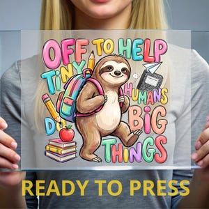 May include: A clear transfer sheet featuring a cartoon sloth wearing a colorful backpack, surrounded by school supplies including pencils, a red apple, and a stack of books. The text reads OFF TO HELP TINY HUMANS DO BIG THINGS.